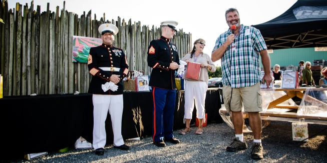 Full dress: Dan Hyatt (right), calls out the winners for the silent auction, with help from two Marines.
