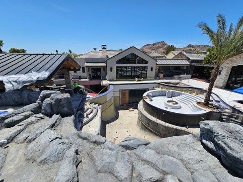The main pool reaches 17-foot depths. The area with the palm tree, to the right, is the floating firepit. Behind it, with the red ladder in front, is a window that will be submerged when the pool is filled.